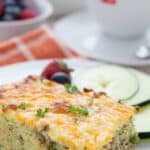 Titled image of a slice of Keto Zucchini Breakfast Casserole on a white plate with coffee in the background.