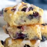 Title image of a stack of Sweet Keto Blueberry Biscuits on a white piece of parchment, with blueberries strewn around.