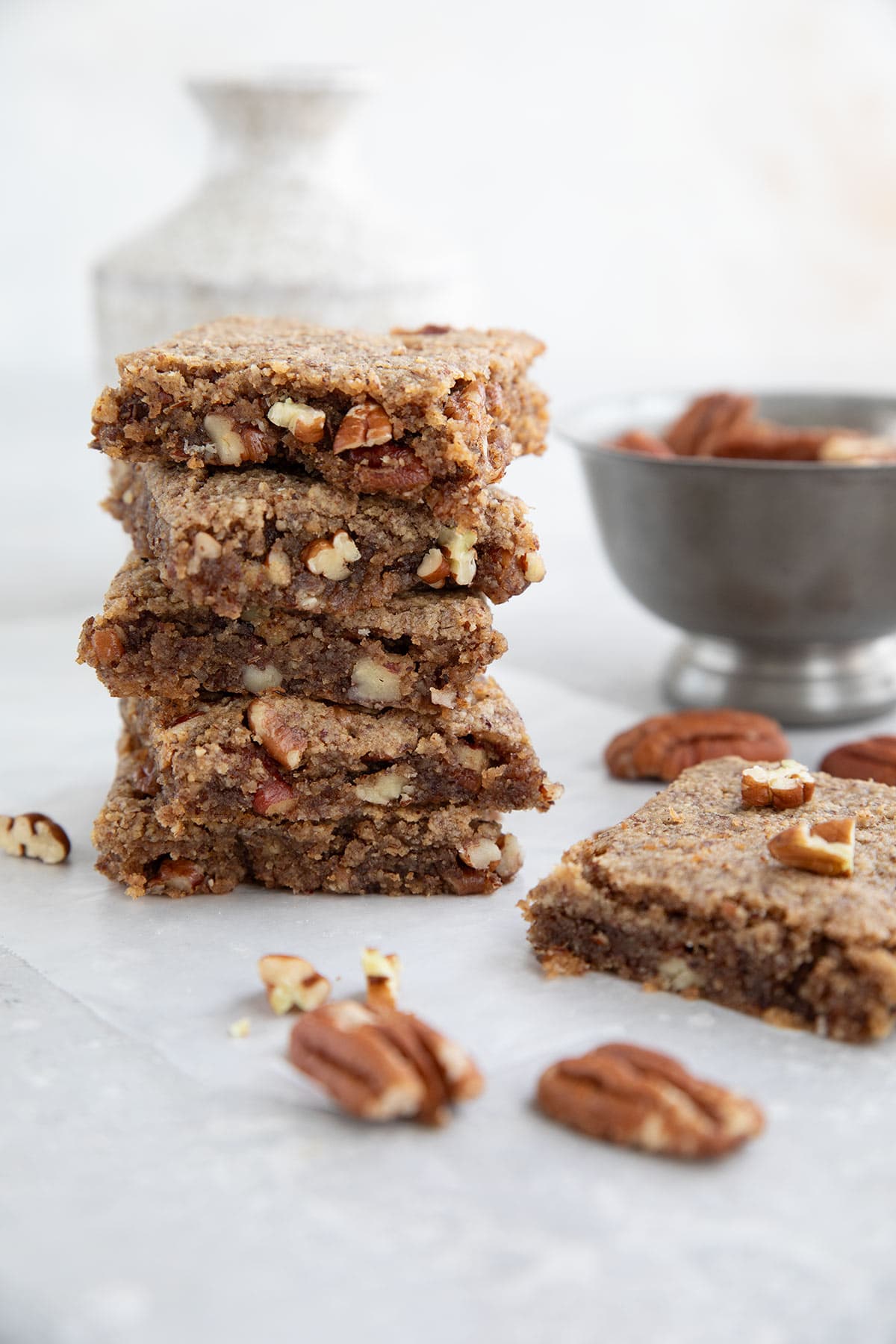 A stack of Keto Chewy Pecan Bars on a gray table.