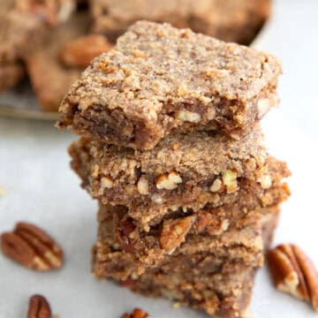 a stack of chewy keto pecan bars with a bite taken out of the top one.