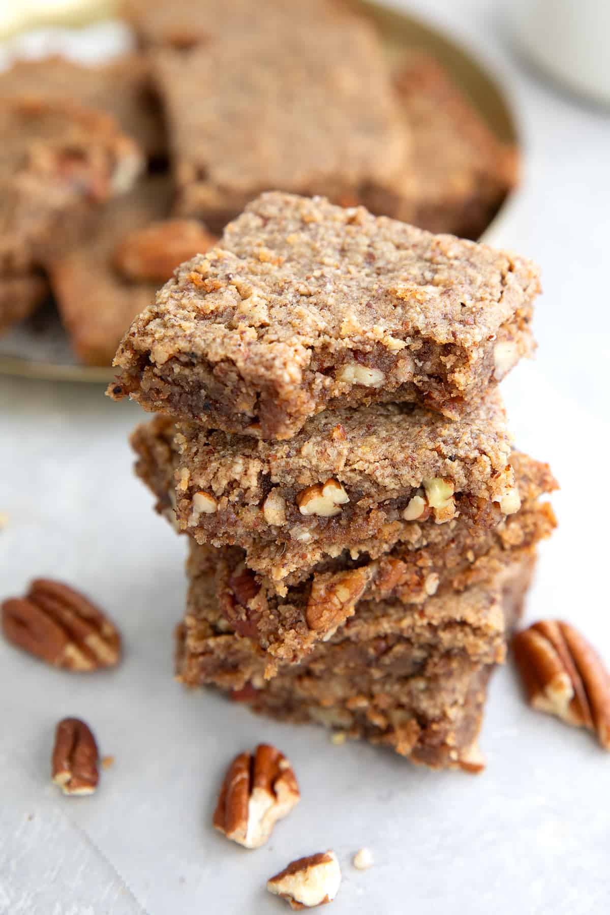 a stack of chewy keto pecan bars with a bite taken out of the top one.