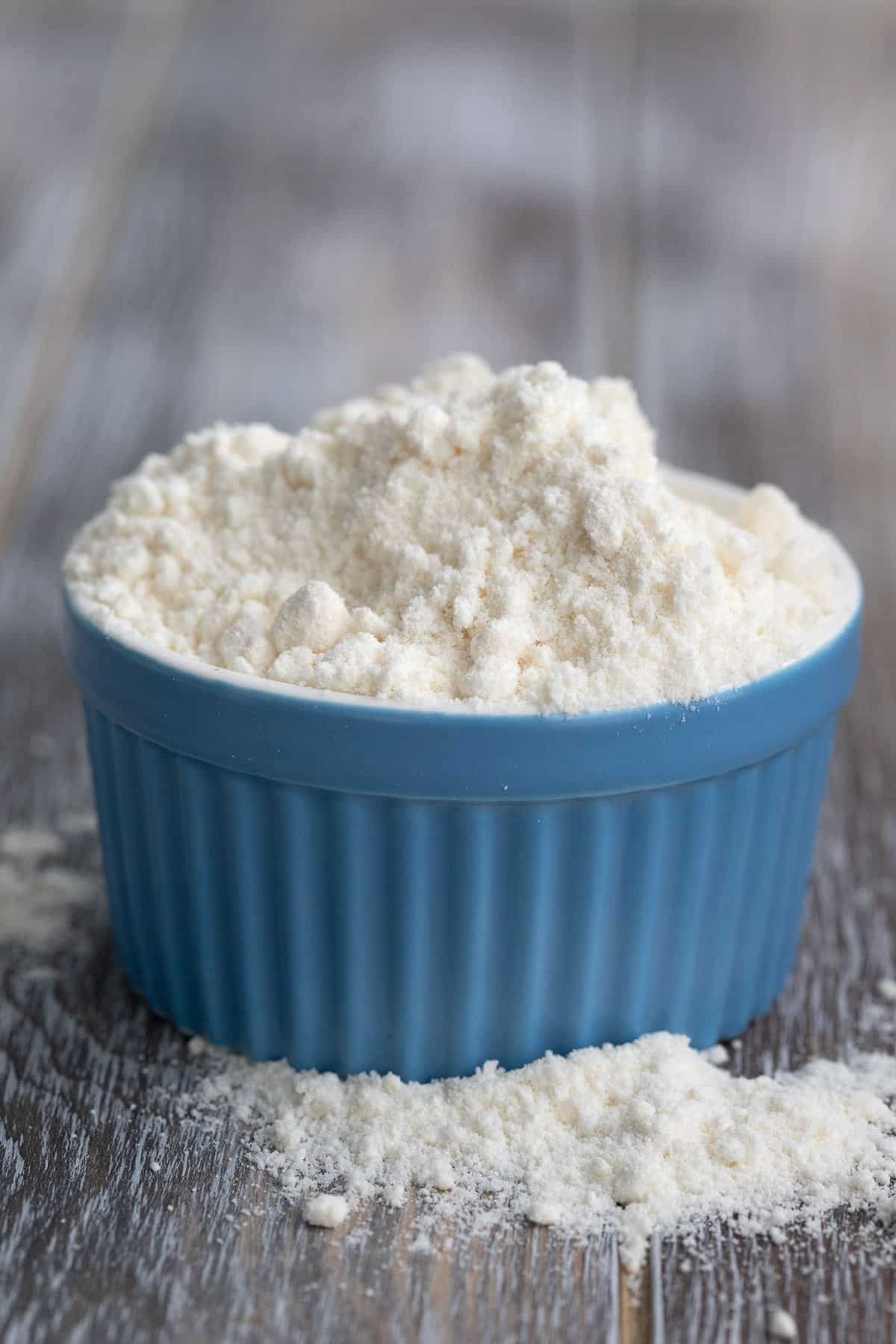 Coconut flour in a blue ramekin on a gray wooden table.