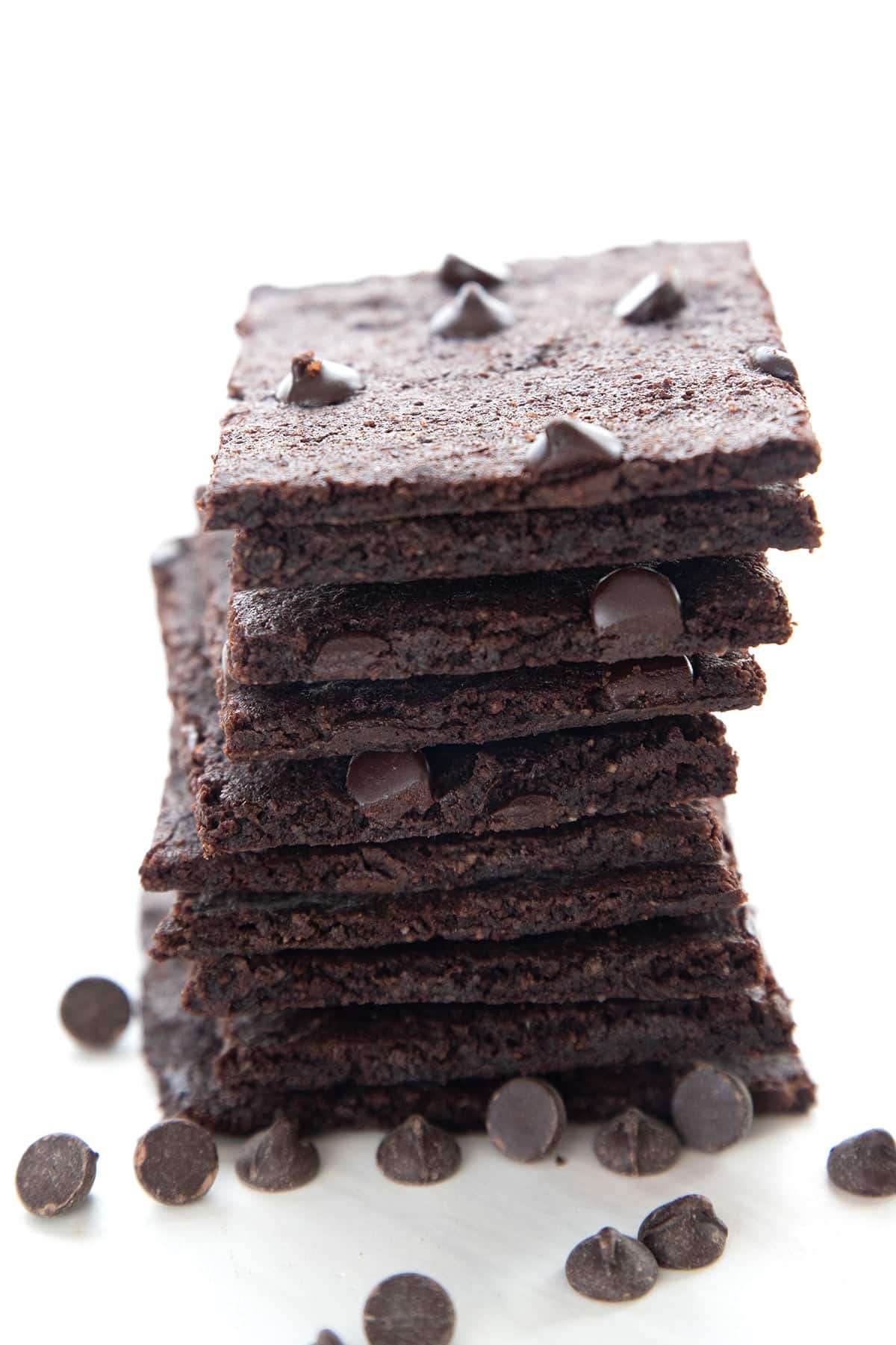 A stack of Keto Brownie Bark on a white background with chocolate chips strewn around.