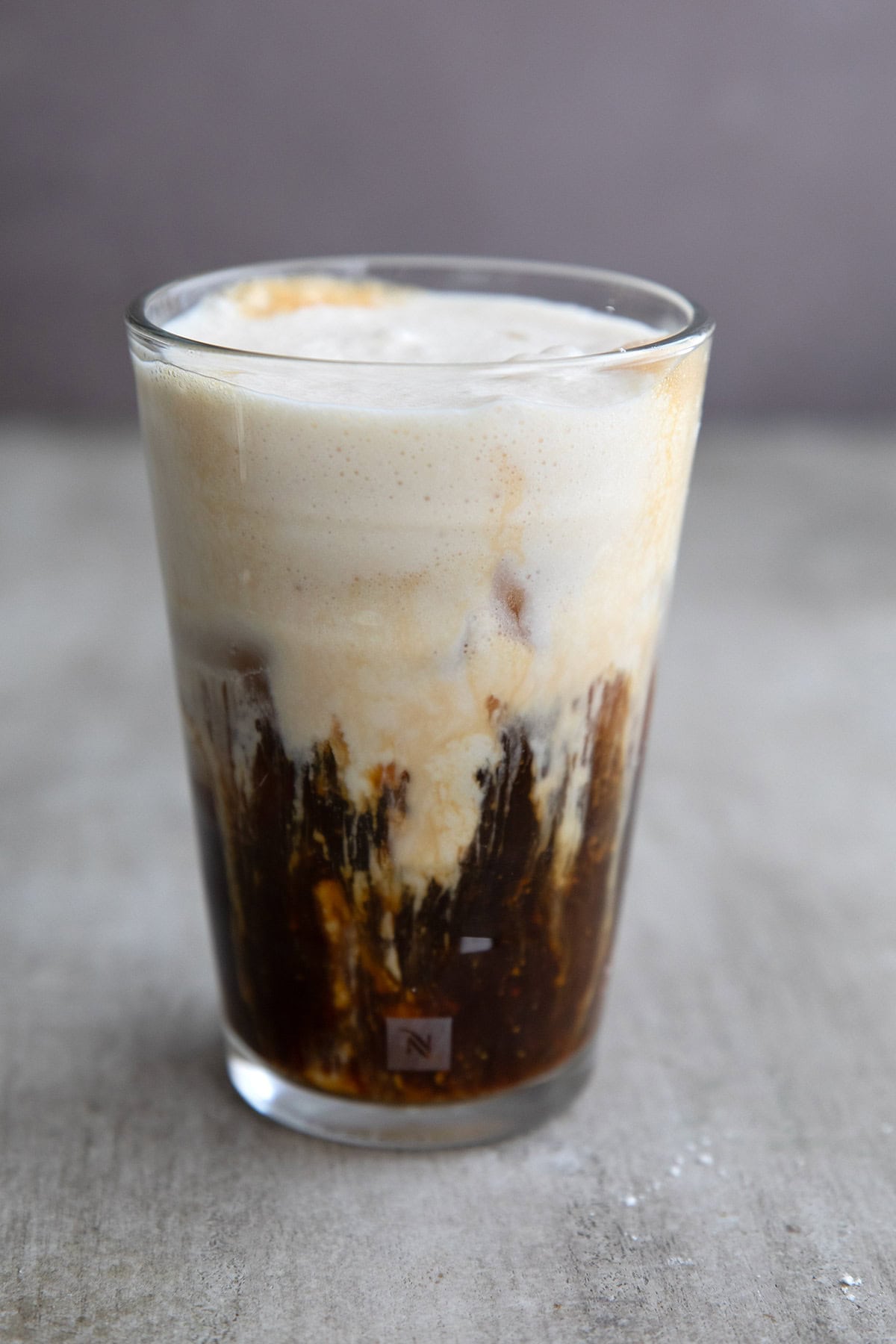 A glass of Iced Protein Coffee in a gray concrete table.