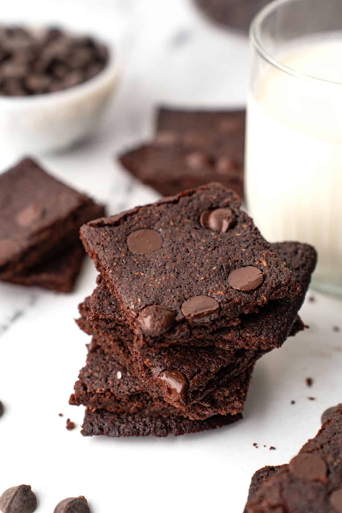 A stack of Keto Brownie Bark beside a glass of milk.