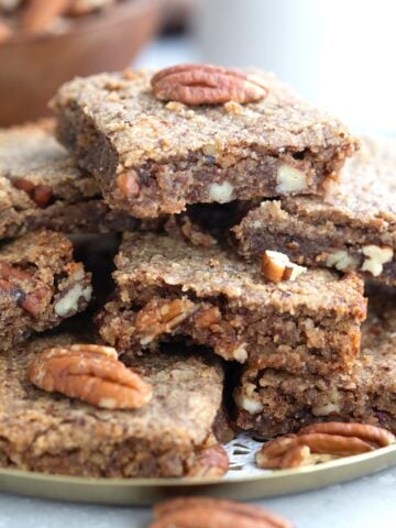 Close up shot of Chewy Keto Pecan Blondies piled up on a plate.