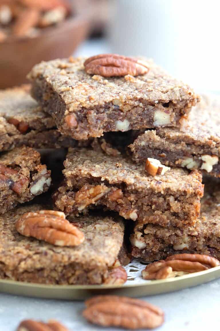 Close up shot of Chewy Keto Pecan Blondies piled up on a plate.