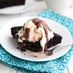 A slice of Keto Slow Cooker Chocolate Cake with ice cream and chocolate sauce on a white plate.