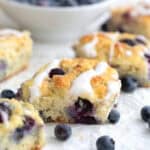 Keto Blueberry Biscuits on a piece of white parchment paper with a bowl of blueberries in the background.