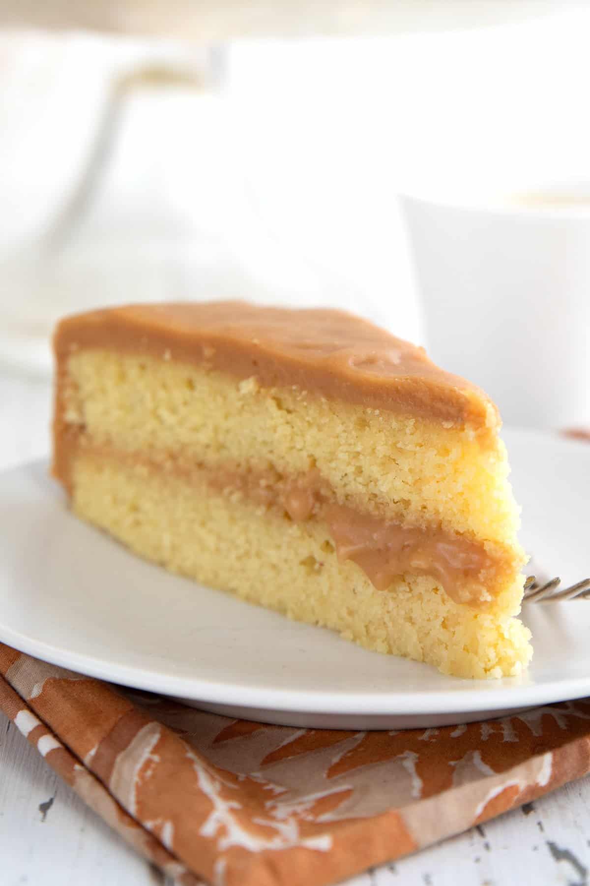 Close up shot of a slice of Keto Caramel Cake with some of the caramel oozing out between the layers.