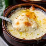 Close up shot of a spoon digging into the broiled cheese topping on a bowl of Chile Relleno Soup.