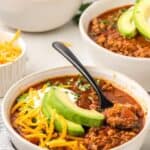 Titled image of three bowls of keto chili on a white table top.