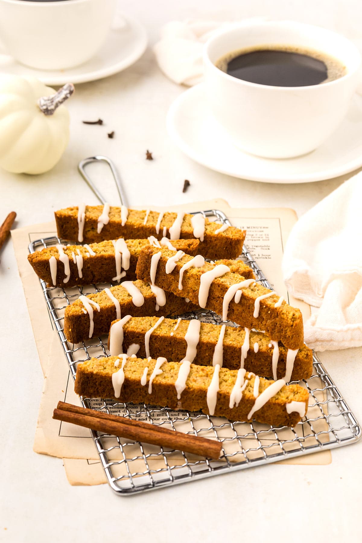 Keto Pumpkin Biscotti cooling on a white rack with a cup of coffee in the background.