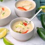 Three bowls of Keto Thai Chicken Soup on a white marble tabletop.