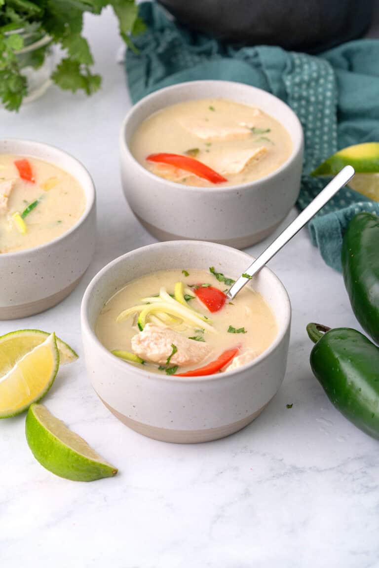 Three bowls of Keto Thai Chicken Soup on a white marble tabletop.