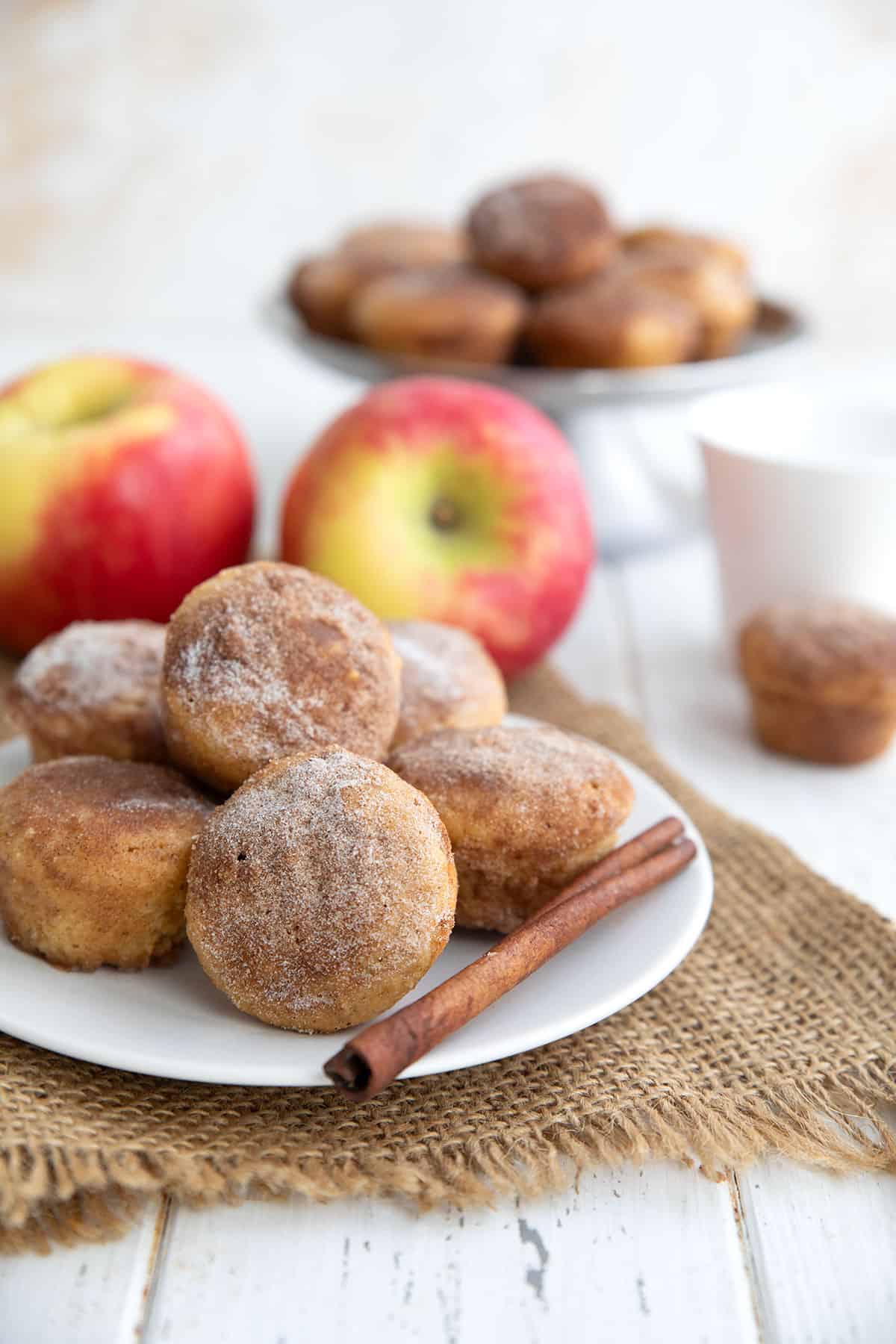 Keto Apple Cider Donut Bites on a white plate over a piece of burlap, with apples in the background.