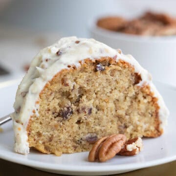 Close up shot of a slice of Keto Butter Pecan Pound Cake on a white plate with pecan halves.