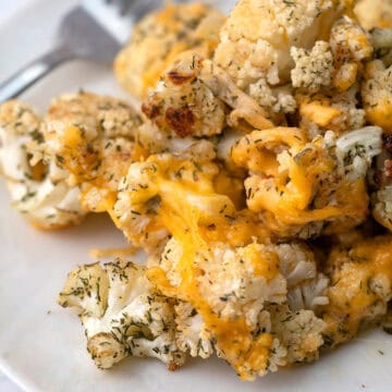 A pile of Cheddar Ranch Roasted Cauliflower on a white plate with a fork.