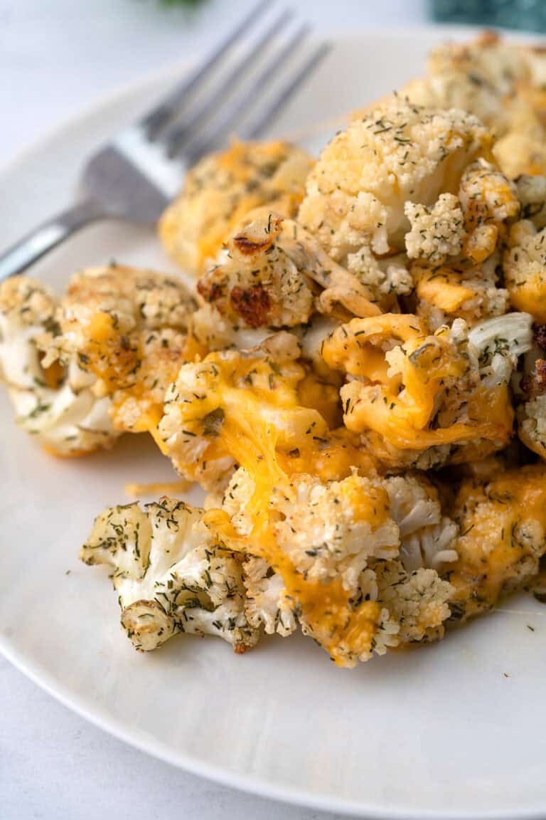 A pile of Cheddar Ranch Roasted Cauliflower on a white plate with a fork.