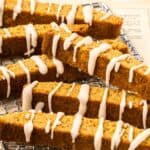 Titled Pinterest image of Keto Pumpkin Biscotti on a wire cooling rack with cinnamon sticks.