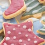 Titled image of a close up shot of Rolled Keto Sugar Cookies with sugar free royal icing. the top cookie is a red star with white polka dots.