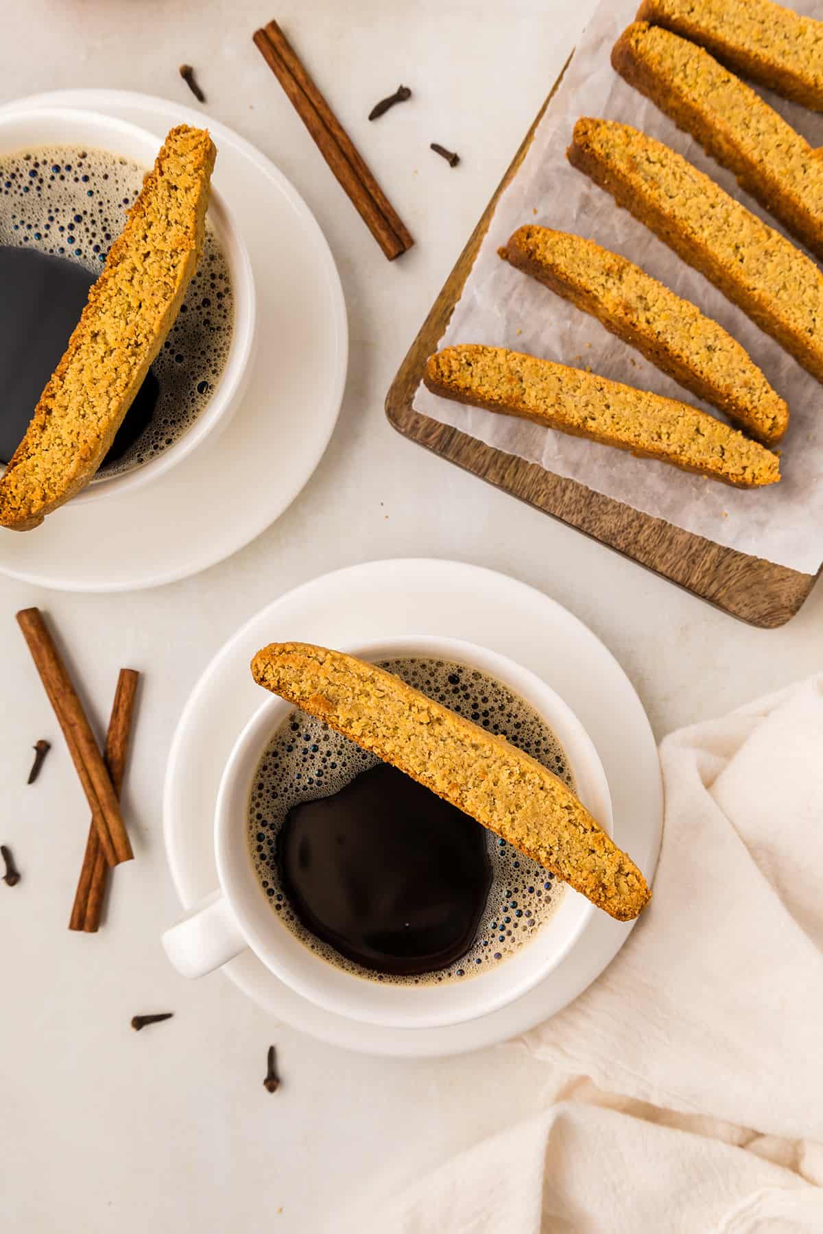 Top down image of Keto Pumpkin Biscotti with cups of coffee on a white table top.