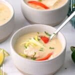 Two bowls of thai chicken soup on a white marble table top.