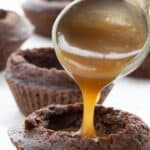 Titled Pinterest image of a tablespoon pouring caramel sauce into a keto brownie bite.