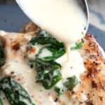 Titled image of a spoon pouring sauce over chicken Florentine on a dark blue plate.