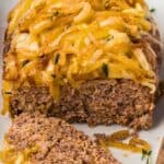 Titled image of Keto French Onion Meatloaf on a white platter with a slice cut out.