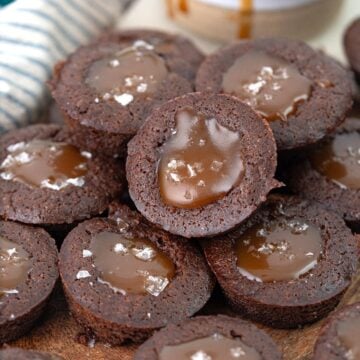 A pile of keto brownie bites filled with caramel cause on a wooden cutting board.