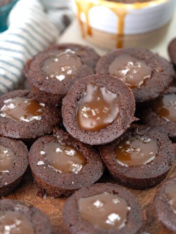 A pile of keto brownie bites filled with caramel cause on a wooden cutting board.