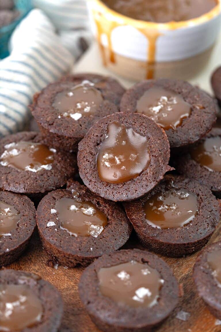 A pile of keto brownie bites filled with caramel cause on a wooden cutting board.