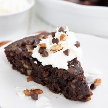 A slice of Keto German Chocolate Pie on a white plate over a dark orange napkin.