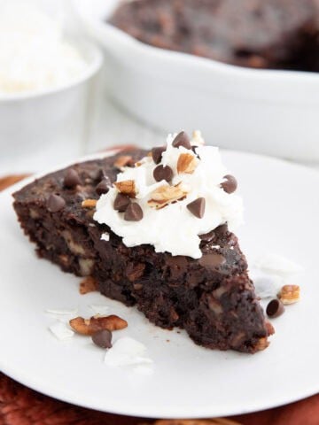 A slice of Keto German Chocolate Pie on a white plate over a dark orange napkin.