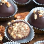 Close up shot of a Keto Pecan Pie Truffle in a fluted candy paper, cut open to show the inside.