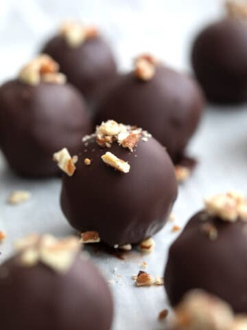 Keto Pecan Pie Truffles on a baking sheet with chopped pecans sprinkled on top.