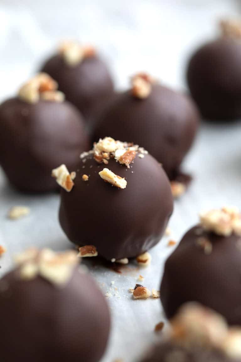 Keto Pecan Pie Truffles on a baking sheet with chopped pecans sprinkled on top.