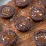 Caramel filled keto brownie bites in rows on a wooden cutting board.