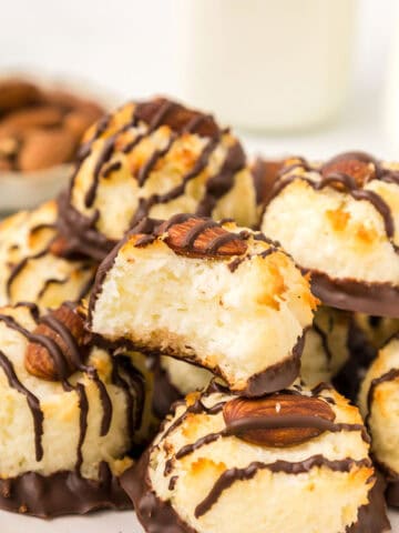 A stack of Keto Almond Joy Macaroons on a white plate with a bite taken out of one.