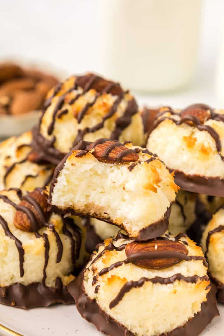 A stack of Keto Almond Joy Macaroons on a white plate with a bite taken out of one.