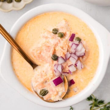 Top down image of a bowl of Smoked Salmon Chowder with a copper spoon in it.