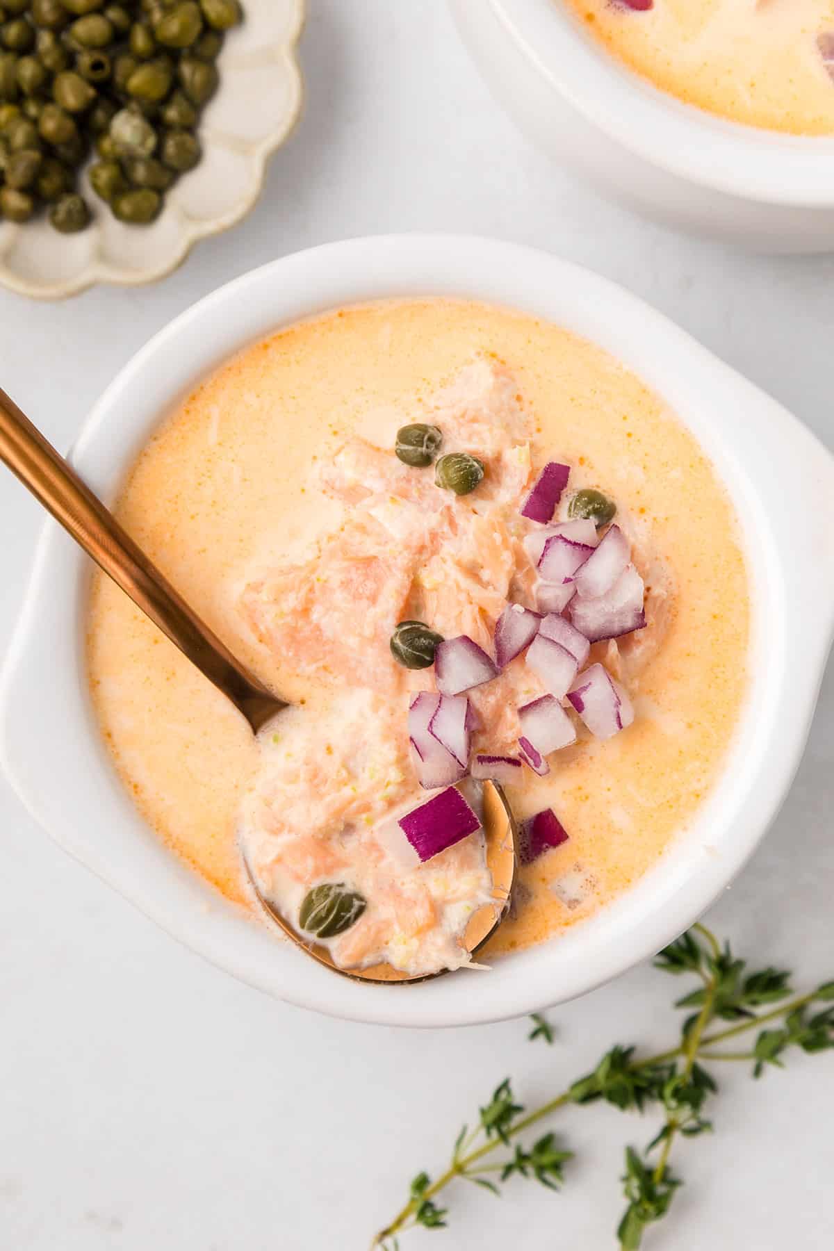 Top down image of a bowl of Smoked Salmon Chowder with a copper spoon in it.