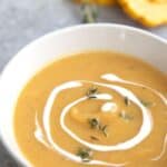 A white bowl filled with Roasted Delicata Squash Soup, with the title in the corner.