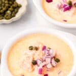 Titled Pinterest image of a white bowl filled with Smoked Salmon Chowder, with capers in small bowl in the background.