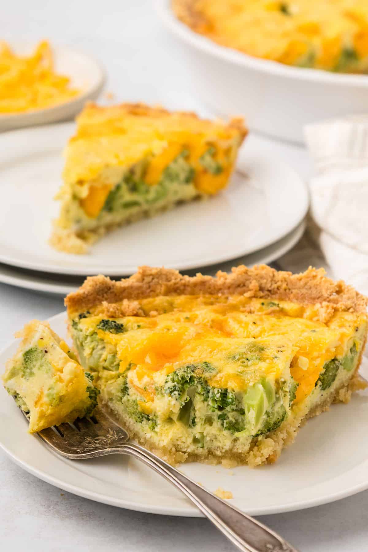 Close up shot of a slice of Keto Broccoli Cheese Quiche with a forkful taken out of it.