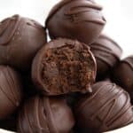 Titled image of Keto Brownie Truffles in a white bowl on a gray wooden table.