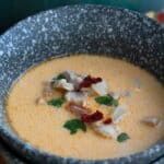 Titled image of a rustic gray bowl of Chipotle Chicken Chowder on a concrete tabletop.