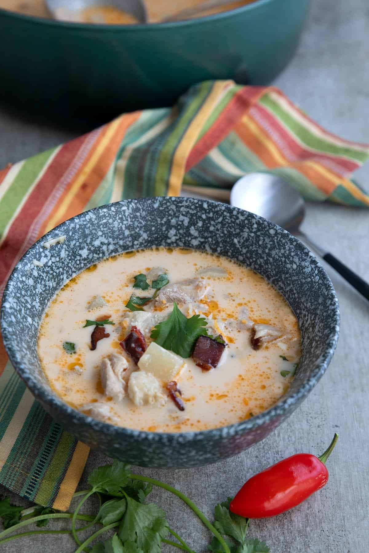 A gray speckled bowl filled with Spicy Keto Chicken Chowder with a colorful striped napkin in the background.