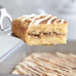 A slice of Keto Cinnamon Roll Coffee Cake being lifted away from the pan on a metal cake spatula.